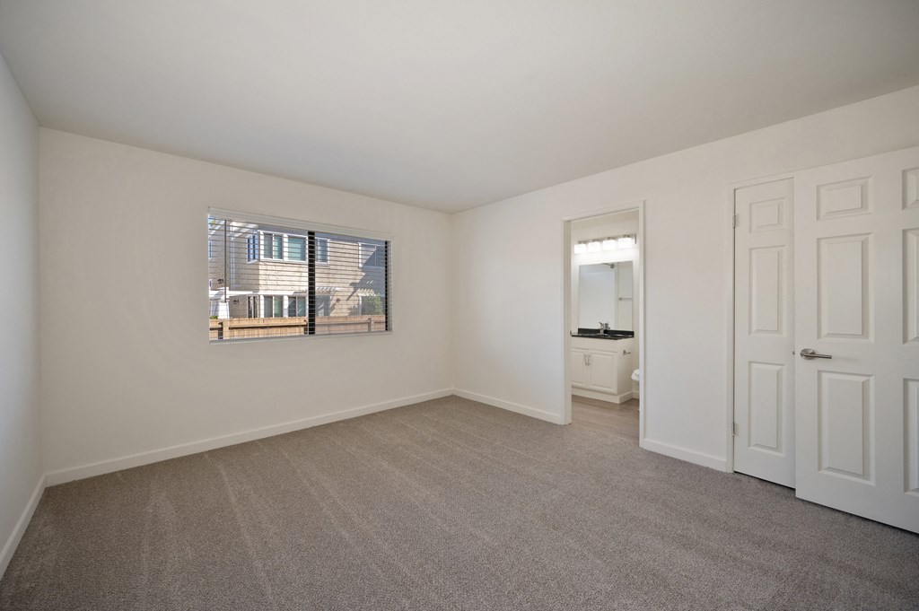 an empty living room with white walls and carpet and a window