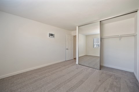 the living room of an apartment with white walls and a mirrored door