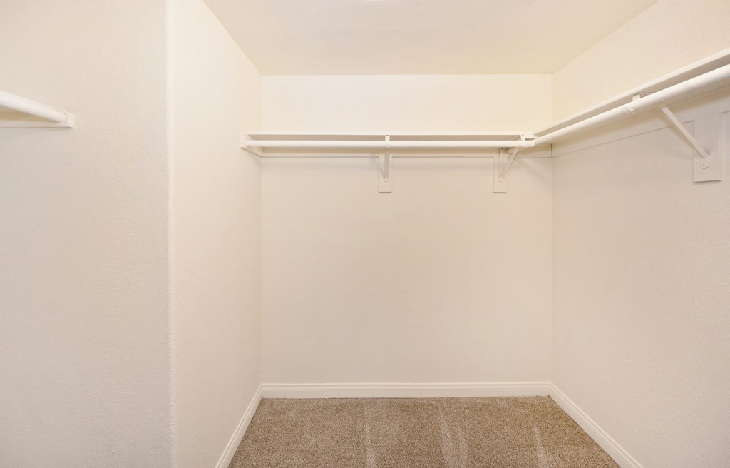 a empty closet with white walls and a carpeted floor