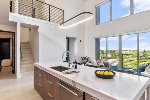 A modern kitchen with light wooden cabinets,  granite countertops, and stainless steel appliances.