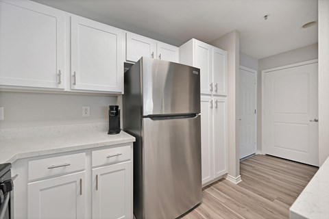 A kitchen with white cabinets, stainless steel appliances, and plank wooden floors