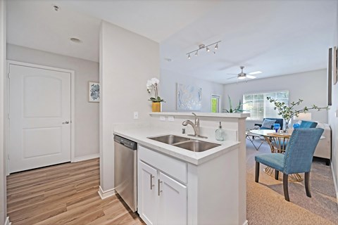 A kitchen with white cabinets, stainless steel appliances, and plank wooden floors