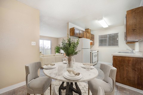 A dining room with carpet and beige walls. The room is staged with a table set for four.