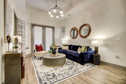 A beautifully staged living room at The Maxwell with wood style plank flooring, white walls, and a lighting fixture.
