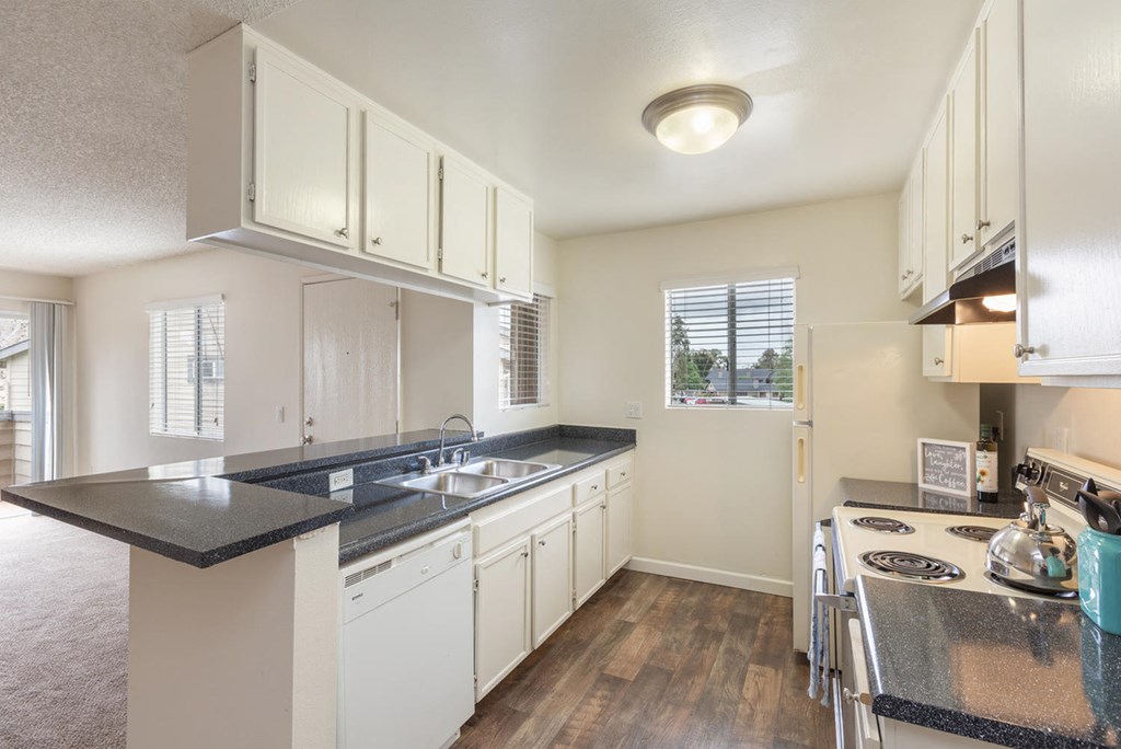 a kitchen with white cabinets and black counter tops