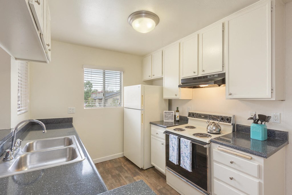 a kitchen with white cabinets and a sink and a stove