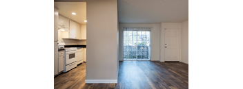 Kitchen with White Appliances and White Painted Cabinets viewed from Living Area with Patio and Entryway Visible