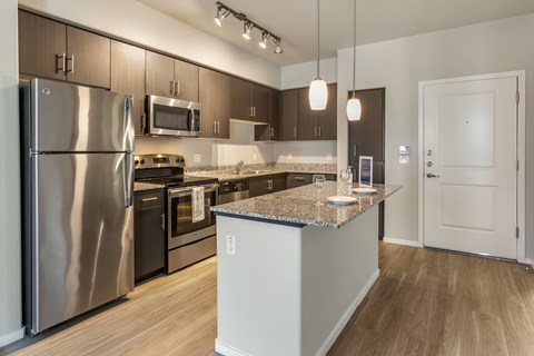 A modern kitchen with stainless steel appliances and wooden flooring.