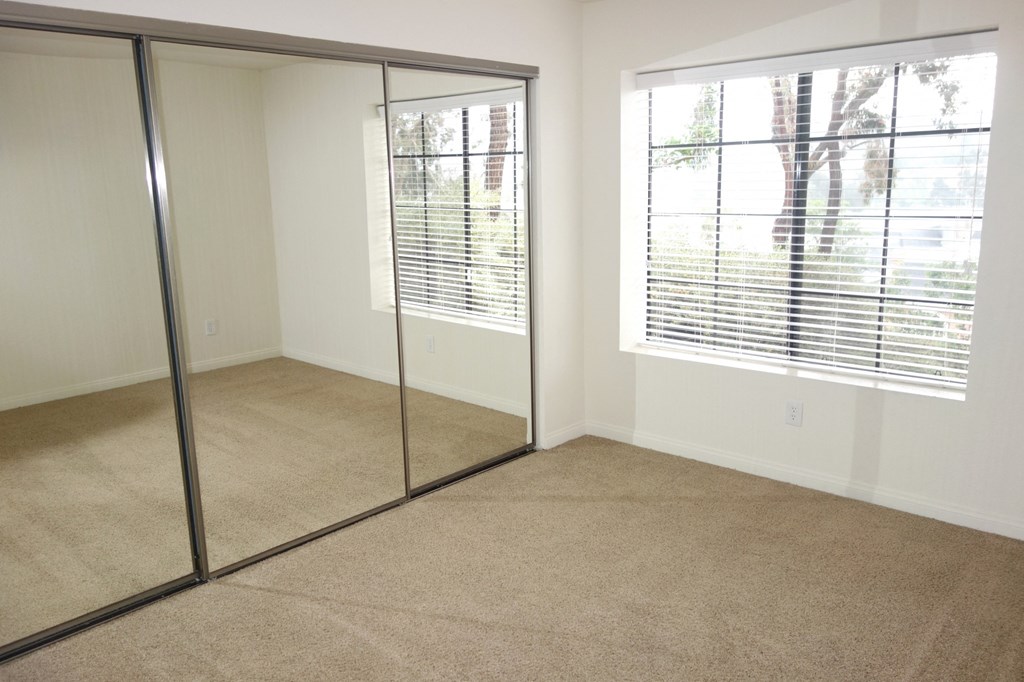 a bedroom with a large window and a mirrored closet