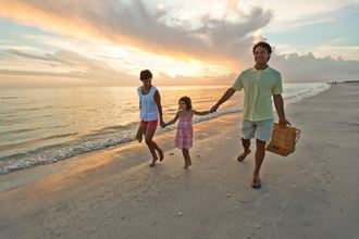 a family walking on the beach at sunset