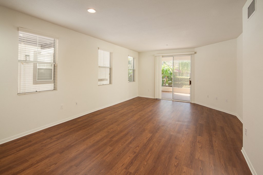an empty living room with wood floors and a door to a patio