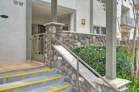 A staircase with a stone railing and yellow steps leading to a door.