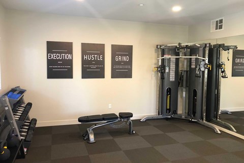 A gym with a wall of three signs that read Execution, Hustle, and Grind.