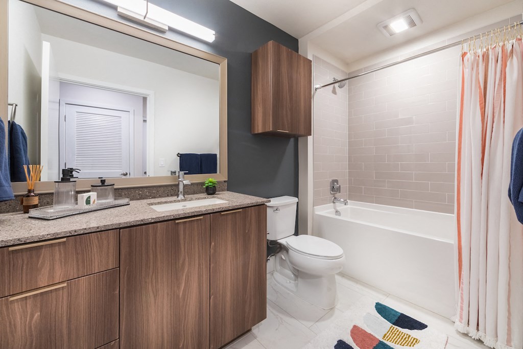 Brass design package bathroom with ceramic flooring, dark wood cabinets, and quartz counters