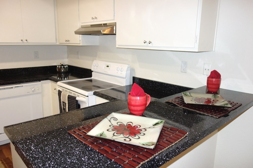a kitchen with white cabinets and black countertops