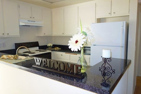 a kitchen with white appliances and a counter with a welcome sign