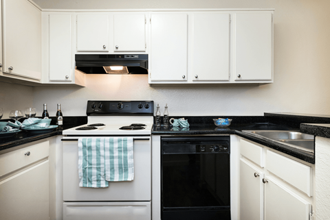 a kitchen with white cabinets and black and white appliances
