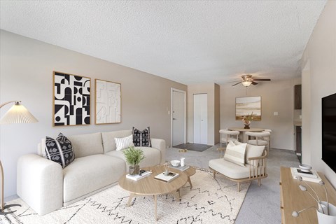 A living room with a white couch, a coffee table, and a television.