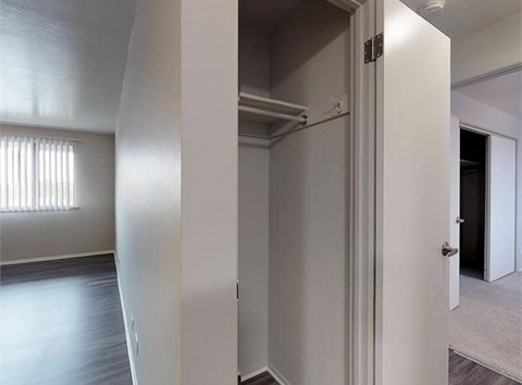 A white closet with a door open to a hallway.