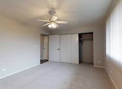 A room with a ceiling fan and carpeted floor.