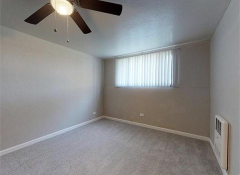 A room with a ceiling fan and a window with blinds.