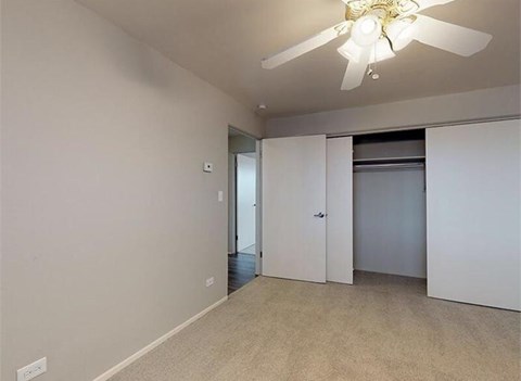 A room with a ceiling fan and a door and closet.
