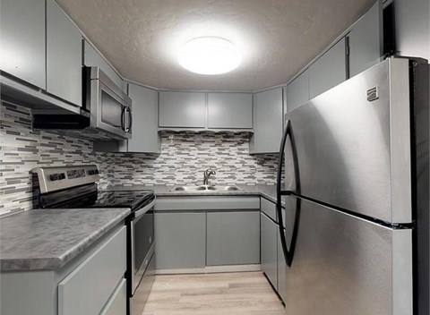 A kitchen with a refrigerator, microwave, and oven.