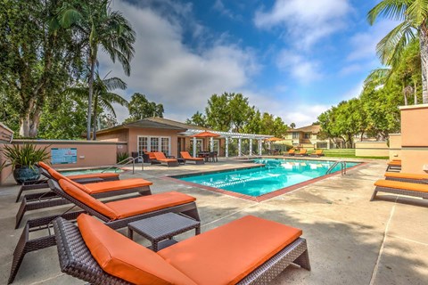 A pool area with sun loungers and a building in the background.