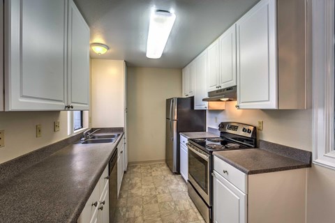 A kitchen with white cabinets and a black refrigerator.