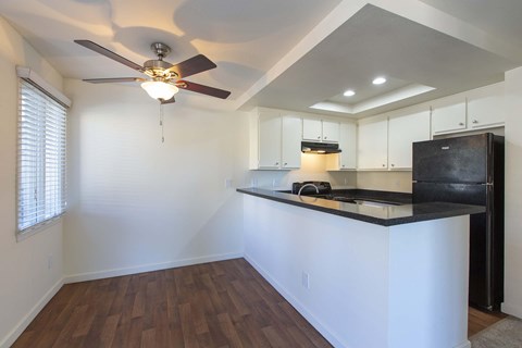 A kitchen with a black refrigerator and wooden floors.
