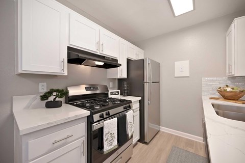 A modern kitchen with white cabinets, quartz countertops, and stainless front appliances.