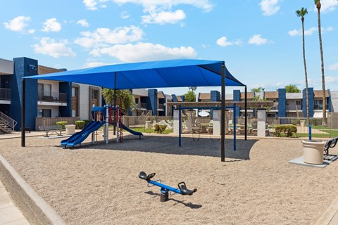 A playground with a blue canopy and a slide.