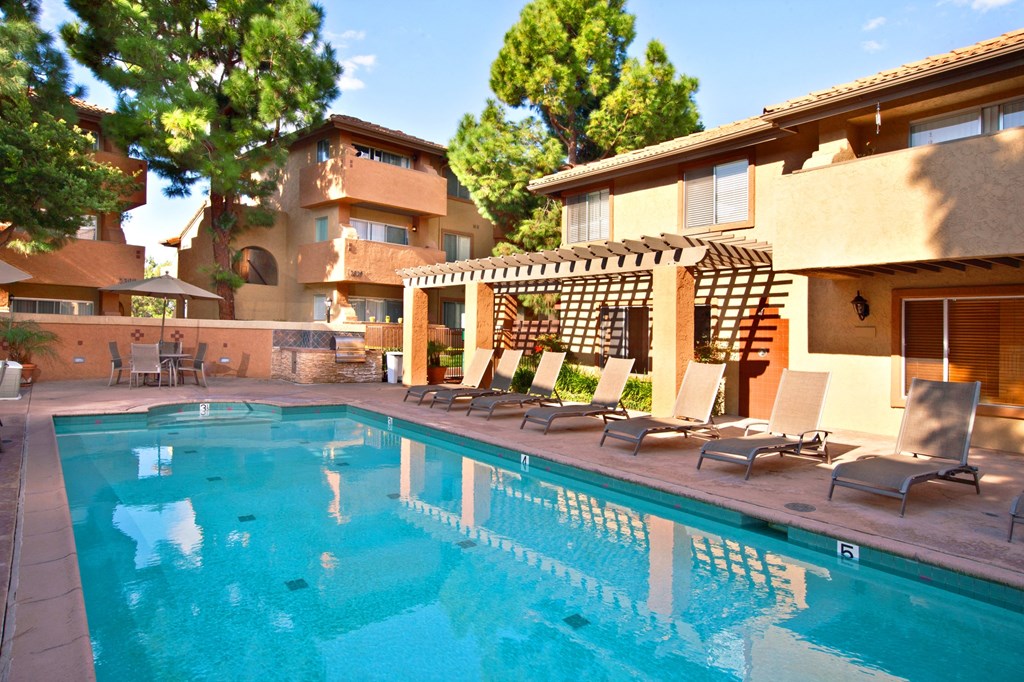 a resort style pool with lounge chairs and a pergola