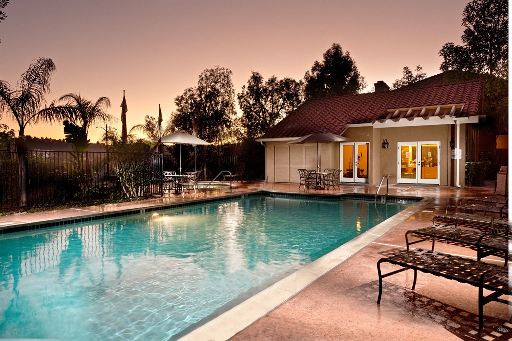a pool in front of a house with a sunset in the background