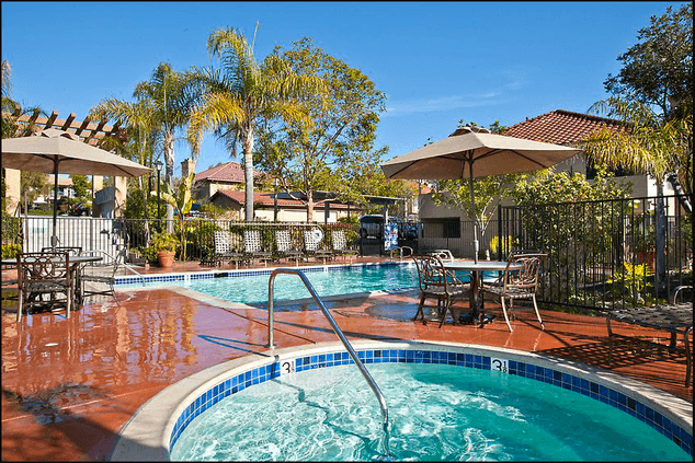 a resort style hot tub with patio furniture and umbrellas