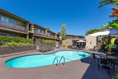 A swimming pool in a backyard with chairs and a table.