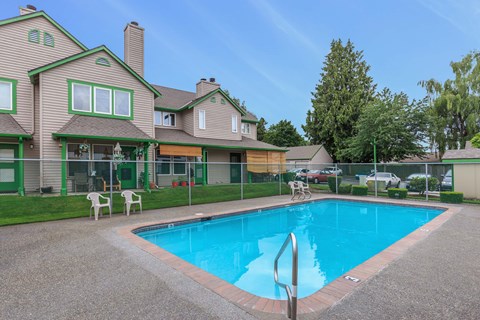 Pool with fence and lawn with view to property exterior and trees.