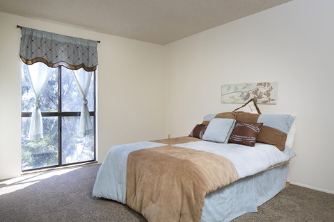 A bedroom with a large bed and a window with curtains.