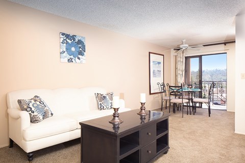 A living room with a white couch, a brown table, and a painting on the wall.