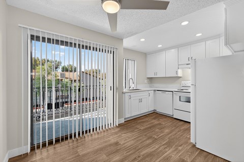 A kitchen with white cabinets and a view of a pool through the window.