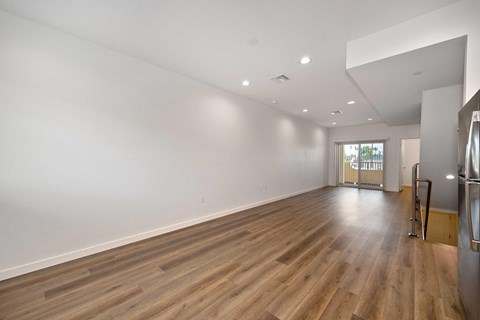 Spacious living room with vinyl wooden flooring and white walls.