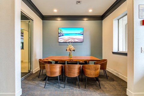 a business conference room with a table and chairs and a tv on the wall