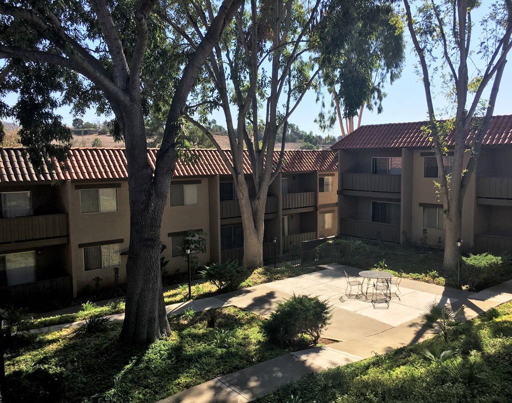 a courtyard with a table and chairs in front of an apartment building