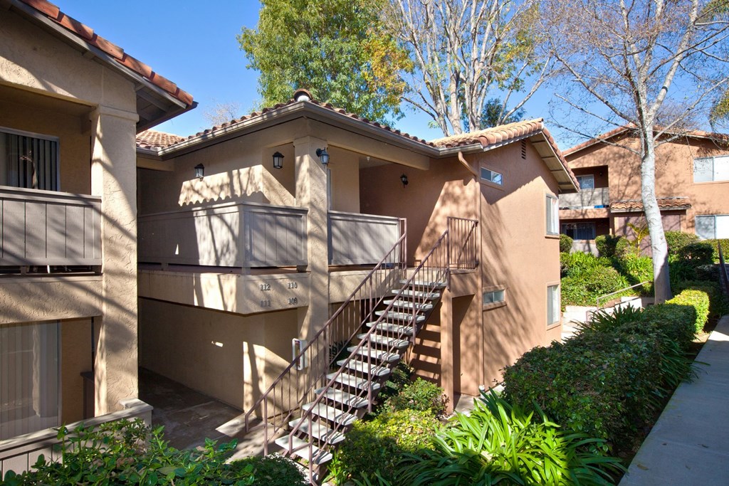a staircase leading up to an apartment building with trees in the background