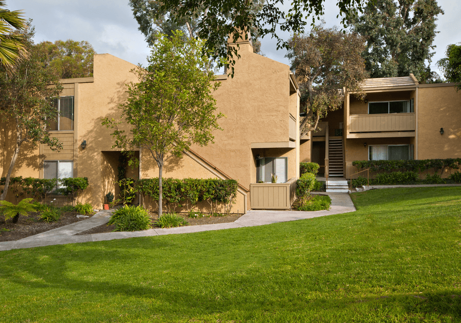an apartment building with a green lawn and trees