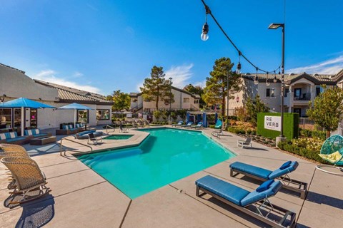 A pool area with sun loungers and a blue umbrella.