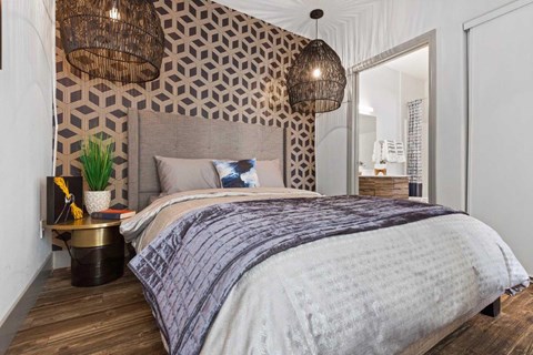 A bedroom with a large bed and a patterned wallpaper.