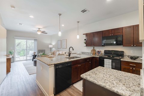A kitchen with granite countertops and dark wood cabinets.