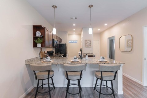 A kitchen with a granite countertop and bar stools.
