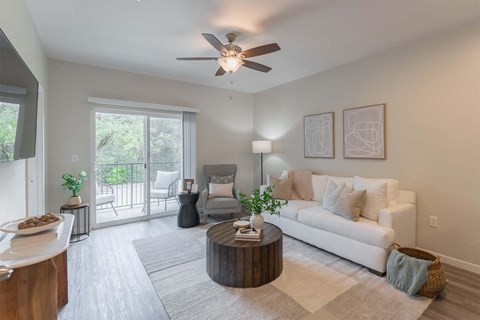 A living room with a white couch, a wooden coffee table, and a ceiling fan.